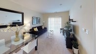Located at The Metro 1 in Hamilton, NJ, this single-floor, one-bedroom, one-bathroom residence offers a well-designed open-concept layout that maximizes functionality and comfort. The living room is carpeted and generously proportioned, featuring sliding glass doors that lead to an outdoor area, filling the space with natural light and providing a seamless indoor-outdoor connection. Adjacent to the living area, the dining space is defined by its proximity to the pass-through kitchen, which boasts rich cherry wood cabinetry, dark granite countertops, wood-look flooring, and a full suite of black appliances including a gas range, microwave, refrigerator, and dishwasher. A convenient in-unit stacked washer and dryer is neatly tucked along the hallway. The bedroom is a peaceful retreat with plush carpeting, a large window dressed with elegant dark drape panels that invite ample natural light, and ample wall space for furnishings. The bathroom is finished with warm-toned tile flooring, a rich wood vanity with a white countertop and large mirror, and a tub-shower combination. Throughout the unit, neutral wall tones and consistent finishes create a cohesive and welcoming ambiance.