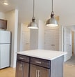 This 990-square-foot, single-floor apartment at 4900 Tanner Dr, Unit 300 in Gillette, Wyoming offers a well-designed 2-bedroom, 1-bathroom layout with modern finishes throughout. The open-concept kitchen is a standout feature, equipped with stainless steel appliances — including a refrigerator, range, microwave, and dishwasher — dark shaker-style cabinetry with sleek hardware, white quartz countertops, and a central island with pendant lighting, ideal for both meal prep and casual dining. Light hardwood flooring runs through the main living and kitchen areas, creating a warm, cohesive feel. The spacious living area opens to a private balcony through a sliding glass door, offering views of the surrounding Wyoming landscape. The primary bedroom spans 200 square feet, features plush carpeting, a window with natural light, and a walk-in closet. The second bedroom is similarly carpeted and bright. The bathroom is finished with a wide dark wood vanity, white countertop, large mirror, and a tub-shower combo. Exposed ductwork adds an industrial design accent visible throughout the unit. A dedicated closet provides additional storage space.