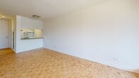 Located on the 8th floor at 2021 Avenue Atwater in Montréal's vibrant Westmount/Shaughnessy Village area, this studio unit offers an efficient and well-designed layout comprising a main living area, an integrated kitchenette, and a full bathroom. The living space is anchored by classic parquet wood flooring in a herringbone pattern, lending warmth and character throughout. Large floor-to-ceiling sliding glass windows flood the room with natural light and frame sweeping views of the Montréal cityscape, creating a bright and airy atmosphere. A built-in closet provides practical storage along one wall. The kitchenette is neatly tucked to one side, featuring light wood cabinetry extending to the ceiling for generous storage, a single-basin sink, a dishwasher, and a neutral countertop — all designed to maximize functionality within a compact footprint. The bathroom is finished with clean white subway tile surrounding a full soaking tub and shower combination, complemented by light tile flooring, a wall-mounted vanity with storage cabinets, and a grey countertop. The overall palette of white walls, natural wood floors, and neutral finishes creates a cohesive, modern, and minimalist ambiance throughout the unit.
