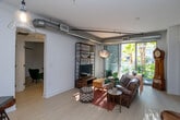 Located in the heart of Hollywood, this single-floor residence at 710 N El Centro Ave offers a thoughtfully designed living environment that balances modern aesthetics with functional comfort. The open-concept living area features light wood-look flooring, crisp white walls, and exposed silver ductwork that lends an industrial-chic character to the space. Large sliding glass doors flood the living room with natural light and provide views of lush palm trees, creating a seamless connection to the outdoors.

The kitchen is well-appointed with white cabinetry, dark countertops, a textured tile backsplash, and stainless steel appliances including a full-size refrigerator and gas range. A mobile island with bar seating adds versatility and encourages casual dining. Track lighting and pendant fixtures provide warm, functional illumination throughout.

The bedroom is a serene retreat with light flooring, a sliding closet, and a window that brings in natural light. An additional room with a built-in closet offers flexible use as a second bedroom, office, or den.

The bathroom is finished with marble-style tile in the tub surround, mosaic tile flooring, warm wood cabinetry, and a clean white countertop vanity. A second bathroom provides additional convenience. The overall ambiance of the residence is bright, modern, and inviting.
