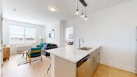 Located at 110 Bergen Tpke in Little Ferry, NJ, this thoughtfully designed two-bedroom, two-bathroom residence offers a modern and efficient single-floor layout. The open-concept kitchen and living area serves as the heart of the home, anchored by a striking quartz-topped island with a waterfall edge and pendant globe lighting above. The kitchen is outfitted with taupe shaker-style cabinetry, a white subway tile backsplash, and a full suite of stainless steel appliances, including a refrigerator, range, and built-in microwave. Warm hardwood-style flooring flows throughout, complementing the bright, neutral palette. The living room receives natural light through large windows and offers views of the surrounding area. Both bedrooms are comfortably proportioned, each featuring windows with exterior views, individual climate control units, and easy access to dedicated closets with wire shelving. The primary bathroom includes a double-sink vanity with quartz countertops, ample cabinetry, a large mirror, and a tiled walk-in shower. The second bathroom features a clean, minimalist design with tile flooring and a soaking tub. Two closets provide generous storage throughout the residence, completing this well-appointed home.