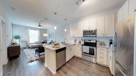 Located at 2170 Snyder Circle in Mount Pleasant, South Carolina, this single-floor residence offers a thoughtfully designed open-concept layout that seamlessly connects the kitchen and living areas. The kitchen is appointed with crisp white cabinetry, granite countertops, a subway tile backsplash, stainless steel appliances — including a range, microwave, and dishwasher — and a peninsula island with pendant lighting overhead. This central hub flows naturally into a bright, welcoming living room featuring wood-style flooring, a ceiling fan, and generous natural light from multiple windows dressed with sheer curtains. The living space provides a comfortable and versatile area suitable for relaxing or entertaining. The bathroom is well-appointed with granite countertops, light wood cabinetry, a large vanity mirror with modern sconce lighting, and a tub-shower combination. Consistent hardwood-style flooring runs throughout the unit, tying each space together with a cohesive, contemporary aesthetic. The soft, neutral color palette across all rooms creates a clean and inviting ambiance, making this Mount Pleasant residence a refined and functional place to call home.