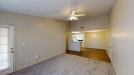 This single-story residence in Robertsdale, Alabama, offers three bedrooms and two full bathrooms within a well-organized, functional floor plan. The living area is a standout feature, distinguished by vaulted ceilings and a ceiling fan with light fixture that enhance the sense of openness. Neutral-toned carpet covers the living space, while hardwood-style flooring extends through the adjoining areas and hallways, creating a clean visual transition throughout the unit.

The kitchen is positioned adjacent to the living area and features a peninsula breakfast bar that connects the two spaces. White cabinetry provides ample storage, and the kitchen is equipped with a coil-burner electric range and a full-size refrigerator. A dining area sits nearby, completing the open-concept arrangement.

A central hallway leads to the three bedrooms, each finished with carpet flooring and neutral wall tones. The primary bedroom includes vaulted ceilings, a ceiling fan, and a large window for natural light. The secondary bedrooms offer comfortable dimensions with windows providing additional daylight.

Both bathrooms include vanities with white cabinetry, single-sink countertops, mirrors, and tub-shower combinations with hardwood-style flooring. The overall aesthetic is clean and straightforward throughout.