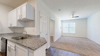 Located at 4115 S Lee St in Buford, Georgia, this 2-bedroom, 1-bathroom single-story home offers a well-organized layout across a comfortable footprint. The galley-style kitchen is a standout feature, outfitted with crisp white shaker cabinetry, granite countertops, a stainless steel sink, and wood-look flooring — providing both style and functionality. It flows conveniently toward the dining area and into the living room, which is brightened by a large window and a ceiling fan overhead.

Both bedrooms are carpeted and filled with natural light from window treatments, with the spacious primary bedroom offering ample room for furnishings. The home includes four closets in total, providing generous storage throughout — including a walk-in closet with multi-tiered wire shelving. The full bathroom features a walk-in shower with a built-in bench and wood-look tile flooring.

A dedicated laundry room with wire shelving adds day-to-day convenience, and multiple utility spaces support practical storage needs. The hallway connects the main living areas to the private bedrooms, creating a logical and efficient floor plan. Clean neutral walls and consistent finishes throughout lend the home a cohesive, move-in-ready aesthetic.