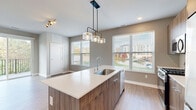 Located at 365 S Moorland Rd in Brookfield, Wisconsin, this well-appointed 2-bedroom, 2-bathroom residence offers a thoughtfully designed single-floor layout with modern finishes throughout. The open-concept kitchen and living area serves as the heart of the home, anchored by a sleek central island with a white quartz countertop, an undermount sink, and rich walnut-toned cabinetry. A striking industrial-style pendant light fixture hangs above the island, complementing the stainless steel appliances and light wood-look flooring. Multiple windows flood the space with natural light and offer views of the surrounding neighborhood. The primary bedroom features plush carpet flooring and an impressive double-closet configuration, providing generous storage. Its en-suite bathroom is elegantly appointed with a dual-sink vanity, wood-toned cabinetry, framed mirrors, and a glass-enclosed shower. The second bedroom is cozy and carpeted, with neutral tones throughout. A second full bathroom offers a single vanity with quartz countertop and a tub-shower combination. A dedicated hallway laundry area houses an in-unit washer and connects seamlessly to the rest of the home. With three total closets, light-toned walls, and consistent modern styling, this residence delivers a clean, contemporary living experience.