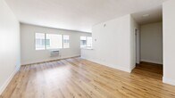 Located at 980 S Menlo Ave in the heart of Los Angeles, CA, this efficiently designed single-floor unit offers a thoughtfully laid-out living experience. The open-concept living room and kitchen area is bright and airy, featuring warm-toned hardwood-style flooring and crisp white walls that create a clean, inviting atmosphere. Large sliding windows allow natural light to fill the living space, enhancing its sense of openness.

The kitchen is a standout feature, showcasing gray shaker-style cabinetry paired with white quartz countertops and a classic white subway tile backsplash. A full suite of stainless steel appliances — including a refrigerator, electric range, over-the-range microwave, and dishwasher — adds a modern, functional edge. A stainless steel sink with a flexible faucet completes the well-appointed space.

The bathroom continues the modern aesthetic with dark charcoal shaker vanity cabinetry, a white countertop, a large mirror, and brushed nickel hardware and grab bars. Rich dark hardwood-style flooring and a marble-accented shower/tub surround lend an elevated finish to the room.

Throughout the unit, the consistent use of neutral tones, quality finishes, and natural light creates a cohesive, contemporary feel well-suited to urban Los Angeles living.