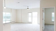 Located at 5214 Browning Ln in Leland, NC, this single-story, three-bedroom, two-bathroom home offers a well-designed open-concept layout with a generous total floor area. The kitchen is a standout feature, boasting white shaker cabinetry, granite countertops, stainless steel appliances, and a central island with a sink and pendant lighting overhead — all flowing seamlessly into the adjacent living room. The living area is carpeted and bathed in natural light, featuring a ceiling fan and a door that opens to an outdoor deck with views of surrounding greenery. The three bedrooms are finished with plush carpet and neutral tones, creating a calm and comfortable atmosphere. The spacious primary bedroom includes its own en-suite bathroom, complete with a dual-sink vanity topped with granite countertops, white cabinetry, and wood-look flooring. A walk-in closet with wire shelving provides ample storage. Two additional walk-in-style closets with wire rack systems serve the remaining bedrooms and hallway. Throughout the home, clean lines, light neutral walls, and consistent finishes create a cohesive, move-in-ready aesthetic well-suited for comfortable everyday living.