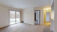 This single-floor, two-bedroom, two-bathroom unit at The Crest in Ann Arbor, Michigan offers a functional and straightforward layout. The living area is carpeted and features a sliding glass door that fills the space with natural light and provides direct access to an outdoor patio with views of surrounding wooded scenery. A pass-through opening connects the living area to the galley-style kitchen, which is equipped with white cabinetry, dark countertops, black appliances including a refrigerator, range, and dishwasher, and hardwood-style flooring. A ceiling fan is present in the adjoining dining or entry area.

Both bedrooms are carpeted and feature dedicated closets with wood-framed sliding doors. The primary bedroom includes its own sliding glass door leading to the patio, providing additional outdoor access and natural light. The second bedroom features a window with wooded views.

Each of the two bathrooms includes a full tub-shower combination with white tile surround, chrome fixtures, and stone-look tile flooring. One bathroom also features a vanity with a dark countertop and white cabinetry. The unit provides a comfortable, well-organized living environment in a natural setting.