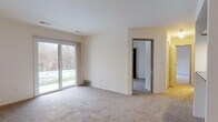 This single-floor, two-bedroom, two-bathroom unit at The Crest in Ann Arbor, Michigan offers a functional and straightforward layout. The living area is carpeted and features a sliding glass door that fills the space with natural light and provides direct access to an outdoor patio with views of surrounding wooded scenery. A pass-through opening connects the living area to the galley-style kitchen, which is equipped with white cabinetry, dark countertops, black appliances including a refrigerator, range, and dishwasher, and hardwood-style flooring. A ceiling fan is present in the adjoining dining or entry area.

Both bedrooms are carpeted and feature dedicated closets with wood-framed sliding doors. The primary bedroom includes its own sliding glass door leading to the patio, providing additional outdoor access and natural light. The second bedroom features a window with wooded views.

Each of the two bathrooms includes a full tub-shower combination with white tile surround, chrome fixtures, and stone-look tile flooring. One bathroom also features a vanity with a dark countertop and white cabinetry. The unit provides a comfortable, well-organized living environment in a natural setting.