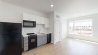 Located at 195 E Main St in the heart of Columbus, Ohio, this modern single-floor unit offers a clean, contemporary design with an efficient and open layout. Light-toned luxury vinyl plank flooring runs throughout the space, creating a cohesive, bright aesthetic that complements the crisp white walls and recessed lighting.

The kitchen is thoughtfully appointed with white upper cabinetry, gray lower cabinets, and a classic white subway tile backsplash. Black Whirlpool appliances — including a refrigerator, electric range, over-the-range microwave, and dishwasher — provide a striking contrast against the light finishes. A stainless steel sink with a modern faucet completes the workspace.

The open living area benefits from a large window that invites natural light and offers views of the surrounding Columbus streetscape. The space feels airy and versatile, with ample room to configure for both living and sleeping arrangements.

The bathroom features a glass-enclosed walk-in shower with a rainfall showerhead, a white vanity with an integrated sink, and matching light wood-toned flooring that ties the space together. The all-white palette gives the bathroom a clean, spa-like quality.

This unit combines functional design with modern finishes, making it a well-suited space in a vibrant downtown Columbus location.