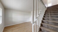 This two-story, 2-bedroom, 1-bathroom home on Martin Luther King Jr Blvd in Columbus, GA offers a well-organized layout across two floors. The main level houses the combined kitchen and living area, where light wood-look flooring runs throughout, creating a clean and cohesive feel. The kitchen is outfitted with gray shaker-style cabinetry, marble-look countertops, black appliances including a gas range, microwave, dishwasher, and refrigerator, as well as an in-unit washer. A bright window allows natural light to fill the space. The open living area is airy and neutral, with crisp white walls and continued wood-look flooring. A white baluster staircase with carpet-treaded steps connects the two floors. Upstairs, two carpeted bedrooms each feature ceiling fans with light fixtures and windows fitted with horizontal blinds, offering natural light and outdoor views. The primary bedroom is a comfortable size with ample room for furnishings. The full bathroom showcases large-format marble-look tile surrounding the tub/shower combo, complemented by gold-toned fixtures, a window, and a white vanity, providing a clean and refined finish throughout.