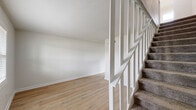 This two-story, 2-bedroom, 1-bathroom home on Martin Luther King Jr Blvd in Columbus, GA offers a well-organized layout across two floors. The main level houses the combined kitchen and living area, where light wood-look flooring runs throughout, creating a clean and cohesive feel. The kitchen is outfitted with gray shaker-style cabinetry, marble-look countertops, black appliances including a gas range, microwave, dishwasher, and refrigerator, as well as an in-unit washer. A bright window allows natural light to fill the space. The open living area is airy and neutral, with crisp white walls and continued wood-look flooring. A white baluster staircase with carpet-treaded steps connects the two floors. Upstairs, two carpeted bedrooms each feature ceiling fans with light fixtures and windows fitted with horizontal blinds, offering natural light and outdoor views. The primary bedroom is a comfortable size with ample room for furnishings. The full bathroom showcases large-format marble-look tile surrounding the tub/shower combo, complemented by gold-toned fixtures, a window, and a white vanity, providing a clean and refined finish throughout.
