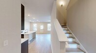 Located at 7405 Fletcher Drive in Chattanooga, TN, this two-story home offers three bedrooms, four bathrooms, and a thoughtfully designed layout spread across two floors. The main level provides a generous open-concept kitchen and living area, where large windows fitted with blinds invite abundant natural light and views of the surrounding neighborhood. The kitchen is a standout feature, showcasing sleek grey cabinetry with gold hardware, white quartz countertops, stainless steel appliances, and light hardwood flooring that extends throughout the main living spaces. A pantry and a dedicated laundry room with wire shelving and hookups add practical convenience on this level. The attached garage is spacious, featuring a two-door automatic opener and an electrical panel, offering ample storage or parking. Upstairs, the primary bedroom is generously proportioned, highlighted by a tray ceiling with a ceiling fan, a walk-in closet with built-in wire shelving, and a private en-suite bathroom complete with large-format tile flooring, a glass-enclosed shower, and a white vanity with quartz countertops. Two additional bedrooms feature light hardwood floors and bright, neutral walls. With four well-appointed bathrooms throughout, this home balances modern style with functional living in a clean, move-in-ready condition.