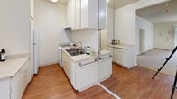 Located at Olive Tree in Torrance, California, this single-floor residence offers a practical and comfortable layout designed for everyday living. The kitchen is outfitted with white cabinetry, a gas range, stainless steel sink, and a white tile backsplash, all set atop warm hardwood-style flooring that lends a clean, cohesive aesthetic. Ample cabinet storage and generous counter space make this kitchen both functional and efficient. The open living and dining area transitions seamlessly from the kitchen, featuring neutral carpet, a ceiling fan with light fixture, and vertical blinds that filter natural light from a sliding glass door. The spacious main living area is bright and airy, with a textured ceiling, soft carpet, and large vertical blinds covering a full sliding door that invites natural light. The bedroom is well-proportioned with carpeted floors, a window with vertical blinds, and a textured ceiling, providing a calm and restful environment. The bathroom features hardwood-style flooring, white vanity cabinetry with a wide countertop, a lighted vanity mirror, and access to a separate shower-tub enclosure. A wall-mounted HVAC vent ensures year-round climate comfort throughout the home. This residence offers a clean, neutral palette that serves as an excellent canvas for personalization.