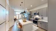 Located at 3700 Governors Dr SW in Huntsville, Alabama, this thoughtfully designed single-story residence combines modern aesthetics with functional living. The open-concept floor plan connects the kitchen, dining, and living areas seamlessly, creating a bright and cohesive environment.

The kitchen is a standout feature, outfitted with gray shaker-style cabinetry, white quartz countertops, a full suite of stainless steel appliances, and a subway tile backsplash. A central island with an undermount sink and seating for multiple guests serves as both a prep space and a casual gathering spot, illuminated by a trio of sleek black pendant lights.

The living area exudes warmth and character, anchored by a bold blue accent wall, large French doors that invite abundant natural light, and hardwood-style flooring that flows throughout. A stacked washer and dryer unit is conveniently integrated into the layout.

The bedroom offers a tranquil retreat with large windows dressed in patterned curtains and blinds, a deep blue accent wall, and a ceiling fan for comfort. The bathroom features a wide vanity with an undermount sink, a large framed mirror, contemporary sconce lighting, and tile flooring. Every detail of this residence reflects a cohesive, modern design sensibility.