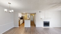 Located at 222 Kyser Blvd in Madison, Alabama, this single-floor 2-bedroom residence offers a clean, modern aesthetic with thoughtfully updated finishes throughout. The open-concept living area is anchored by a tiled fireplace and features warm wood-look flooring, a ceiling fan, and a sliding glass door that invites natural light and outdoor access. The kitchen is a standout, outfitted with crisp white shaker cabinetry, granite countertops that extend to a peninsula breakfast bar, stainless steel appliances including a refrigerator and dishwasher, and a undermount sink — all beneath a textured ceiling with flush lighting. A hallway connects the main living spaces to the two bedrooms, each carpeted for comfort and equipped with ceiling fans. The primary bedroom includes a private en-suite bathroom featuring granite countertops, a large vanity mirror, wood-look flooring, and a tiled tub/shower combination. A second full bathroom serves the remaining bedroom. Neutral gray tones and white trim create a cohesive, move-in-ready feel throughout the entire residence.
