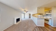 This single-floor residence offers a thoughtfully arranged layout that balances comfort and functionality. The entry opens onto a transitional area with wood-look flooring that flows into the main living space, where plush carpeting sets a warm, inviting tone. The spacious living room is a standout feature, centered around a white brick fireplace with a tile hearth and topped by a ceiling fan with a light fixture. A sliding glass door allows abundant natural light to fill the room while providing access to the outdoors, and a side window further brightens the space.

The kitchen is designed as a galley-style layout with ample upper and lower cabinetry, white countertops, a double-basin sink, and white appliances including a refrigerator and range. A pass-through counter connects the kitchen to the living area, enhancing the open feel of the shared spaces and making the kitchen easily accessible.

The bedrooms are carpeted and finished with neutral-toned walls, each offering a calm, versatile space. Natural light enters through windows fitted with blinds, providing privacy while maintaining brightness. The overall color palette throughout the home is light and neutral, creating a clean, cohesive aesthetic. The single-floor layout ensures easy navigation and a seamless flow between all areas of the home.