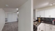 Located at 3802 N 27th St in Phoenix, Arizona, this single-floor unit offers a thoughtfully designed layout ideal for comfortable everyday living. The kitchen is appointed with crisp white cabinetry, dark granite-style countertops, a mosaic tile backsplash, and a double stainless steel sink, creating a clean and functional workspace that opens toward the main living area. A half-wall divider separates the kitchen from the rest of the unit, maintaining an open feel while providing definition between spaces. The living area features durable wood-look plank flooring, a ceiling fan with integrated lighting, and vertical blinds that allow for light control and privacy. A decorative stacked-stone accent wall adds a touch of texture and character to the space. The bathroom is well-appointed with wood-look tile flooring, white cabinetry with dark countertops, and a full tub-and-shower combination. The bedroom includes plush carpeting and features a dedicated walk-in closet with built-in shelving, offering generous storage. Textured ceilings are present throughout, and the overall color palette of whites and neutral grays gives the unit a clean, contemporary appearance throughout.