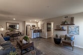 Located on Live Oak Street in Hesperia, California, this single-story residence offers a thoughtfully designed open-concept floor plan that seamlessly connects the main living areas. Light-toned hardwood-style flooring flows throughout, enhancing the sense of openness and continuity across the space.

The spacious living room serves as the heart of the home, featuring a large window that allows natural light to fill the room, a wall-mounted television, and direct sightlines to the kitchen and dining areas. A dedicated dining nook provides an intimate setting with rustic wood furnishings and warm décor accents.

The kitchen is well-appointed with white shaker-style cabinetry, light quartz countertops, stainless steel appliances including a refrigerator, gas range, and microwave, and a peninsula with bar seating — ideal for casual dining or entertaining.

The unit includes two bedrooms, each finished with neutral tones, hardwood-style flooring, and sliding-door closets offering generous storage. The bathroom features a clean, functional design with a single vanity, mirror, and shower/tub combination.

Throughout the residence, recessed lighting and a neutral color palette create a bright, welcoming ambiance well-suited for comfortable everyday living in the high desert community of Hesperia.