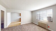 Located at 4219 Allendorf Dr in Cincinnati, Ohio, this single-floor unit offers a straightforward, functional layout designed for comfortable everyday living. The floor plan reveals several interconnected rooms, including a living area, kitchen, bedrooms, and a full bathroom, all arranged for practical flow and accessibility.

The living and bedroom areas are finished with neutral-toned wall-to-wall carpeting, contributing to a warm and quiet atmosphere. Each carpeted room is equipped with a classic cast-iron radiator, providing reliable radiant heat, along with windows fitted with horizontal blinds that allow for natural light control. Ceiling fans are present in the bedroom spaces, adding to year-round comfort.

The kitchen features a galley-style configuration with warm wood-toned cabinetry lining both sides, offering generous upper and lower storage. A double-basin stainless steel sink, laminate countertops, a white refrigerator, and a dishwasher complete the space. Light tile flooring extends through the kitchen, providing a clean contrast to the carpeted rooms. A window at the end of the kitchen brings in additional natural light.

The bathroom is finished with white tile surrounding a full tub-and-shower combination, complemented by a pedestal sink and a frosted glass window, maintaining brightness while ensuring privacy.