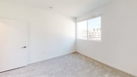 Located at 1446 Tamarind Ave in the heart of Hollywood, Los Angeles, this modern single-floor unit offers a clean, contemporary design throughout. The open-concept living area features light wood-style flooring, crisp white walls, and track lighting, creating a bright and airy atmosphere. A sliding glass door leads to a private balcony, allowing natural light to pour in while offering views of the surrounding neighborhood, including glimpses of palm trees that define the Southern California landscape.

The kitchen is thoughtfully designed with warm wood cabinetry, white quartz countertops, a stainless steel sink, and a full suite of stainless steel appliances including a gas range, microwave, and refrigerator. A peninsula counter connects the kitchen to the living space, making it ideal for both cooking and entertaining.

The bedrooms are carpeted for comfort, featuring white walls and windows that invite natural light. The bathroom is finished to a high standard, showcasing large-format tile flooring, a tub-shower combination enclosed by sliding glass doors with striking marble-style tile surround, a wood-toned vanity, and a wall-mounted mirror. The overall aesthetic is clean, modern, and move-in ready.