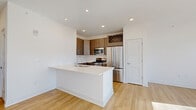 This 700 square foot apartment in Hobart, Indiana, offers a thoughtful blend of comfort and functionality. The open-concept design seamlessly integrates the kitchen and living area, creating a spacious feel. The modern kitchen boasts sleek stainless steel appliances, including a refrigerator, stove, and built-in microwave. Wood-toned cabinets provide ample storage, complemented by a unique wine rack above. A white quartz countertop extends to form a breakfast bar, perfect for casual dining or entertaining.

The living area features hardwood floors that extend throughout the apartment, adding warmth and continuity. Large windows and a glass door leading to a balcony flood the space with natural light, offering views of the surrounding area. The bedroom, measuring 150 square feet, provides a cozy retreat with ample space for a queen-sized bed and additional furniture. A ceiling fan ensures comfort year-round.

The bathroom maintains the apartment's modern aesthetic with a wood-toned vanity and clean white fixtures. A closet off the bedroom offers additional storage space. The apartment's neutral color palette and contemporary fixtures create a canvas for personalization, suitable for various styles and preferences. This efficient one-bedroom apartment combines style and practicality in a compact 700 square foot layout.