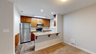 Located in Bothell, WA, this single-floor, 3-bedroom, 2-bathroom home offers a well-organized layout across a comfortable footprint. The spacious living room serves as the heart of the home, highlighted by a brick-surround fireplace with a white mantel and large sliding glass doors alongside a window that flood the space with natural light and provide outdoor views. Soft carpeting flows throughout the living areas and bedrooms, contributing to a warm, cohesive ambiance. The kitchen is thoughtfully designed with rich warm-toned wood cabinetry, tile backsplash, stainless steel appliances including a refrigerator, range, and microwave, and a granite-topped peninsula with a breakfast bar overhang — ideal for casual dining. Wood-look flooring grounds the kitchen area. The primary bedroom offers a generous layout with access to the hallway, while the two additional bedrooms each feature plush carpet, neutral walls, and sliding closet doors with built-in racking. Both bathrooms are appointed with granite-topped vanities, wood-toned cabinetry, and full tub-shower combinations with clean white surrounds and wood-look flooring. A connecting hallway ties the bedroom wing together efficiently, completing this functional and comfortable home.
