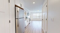 Located at 215 Fairmount Avenue in Lynn, Massachusetts, this thoughtfully designed one-bedroom, one-bathroom unit offers a clean, modern aesthetic throughout its efficiently organized single-floor layout. Light-toned hardwood-style flooring runs continuously through the space, complementing the crisp white walls and creating a bright, cohesive feel.

The open-concept kitchen and living area serves as the heart of the unit. The kitchen is outfitted with white shaker-style cabinetry featuring matte black hardware, a classic white subway tile backsplash, light quartz countertops, and a full suite of stainless steel appliances including a refrigerator, electric range, over-the-range microwave, and dishwasher. Recessed lighting illuminates the kitchen, while a large window at the end of the living area floods the space with natural light and offers views of the surrounding neighborhood.

The bedroom is a well-proportioned, serene retreat with warm hardwood-style flooring, white walls, and an expansive window dressed with blinds that allow for adjustable natural light. Three closets throughout the unit provide generous storage options. The bathroom is clean and modern, finished in white with coordinating flooring. An in-unit laundry area adds everyday convenience, rounding out this well-appointed home.