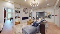 Located on Milledgeville Road in Augusta, Georgia, this single-story clubhouse facility presents a thoughtfully designed communal space that blends contemporary aesthetics with practical functionality. The building's soaring double-height ceilings in key areas flood the interior with natural light through expansive transom windows, creating an open and welcoming atmosphere throughout.

The main lounge serves as the heart of the space, anchored by a floor-to-ceiling stacked stone fireplace wall with built-in shelving and a striking oversized clock as a focal point. A plush sectional sofa, layered rugs, and a sculptural multi-arm chandelier contribute to the warm, sophisticated ambiance. Adjacent seating areas feature curated abstract artwork and built-in workstation surfaces for casual use.

The kitchenette is a standout feature, showcasing sleek white cabinetry, quartz countertops, blue-gray subway tile backsplash, rich wood open shelving, and recessed accent lighting. It is equipped with a beverage refrigerator, microwave, and coffee station. Bar-height seating adds a social element to this well-stocked area.

Two dedicated meeting rooms offer distinct settings—one with a rectangular conference table beneath a modern brass chandelier, and another with a round table and wall-mounted display. Light wood flooring runs throughout, and large windows in nearly every room provide views of the outdoor pool area and surrounding community.