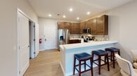 Located at 264 Passaic Ave in Fairfield, NJ, this thoughtfully designed 2-bedroom, 2-bathroom residence offers a seamless blend of modern style and functional living across a single floor. The open-concept layout connects the kitchen and living areas, creating an inviting, cohesive space ideal for both everyday living and entertaining.

The kitchen is outfitted with rich dark-stained cabinetry, stainless steel appliances including a gas range, built-in microwave, and a French door refrigerator, all complemented by crisp white quartz countertops and a subway tile backsplash. A peninsula with bar seating adds convenient casual dining space. Light wood-style flooring runs throughout the main living areas, enhancing the bright, airy ambiance.

The living room features natural light from windows dressed with roman shades, warm neutral tones, and recessed lighting. Both bedrooms are generously sized with plush carpeting and ample closet space. The primary bedroom includes an en-suite bathroom with a frameless glass walk-in shower finished in white subway tile and chrome fixtures. The second full bathroom offers a tub-shower combination with a dark wood vanity and large-format tile flooring. This residence delivers a polished, move-in-ready experience with refined finishes throughout.
