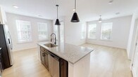 Unit 1311 at 1200 Riverfront is a well-appointed 2-bedroom, 2-bathroom apartment spanning 940 square feet on a single floor in Little Rock, AR. The open-concept kitchen and living area serves as the heart of the unit, showcasing a large granite-topped island with an undermount sink and matte black faucet, rich wood cabinetry, stainless steel appliances, a subway tile backsplash, and bold pendant lighting. Light hardwood flooring runs throughout the main living areas, enhancing the bright, airy ambiance. The primary bedroom, at 160 square feet, features plush carpeting, a ceiling fan, and a window with outdoor views. Its ensuite bathroom is highlighted by a striking blue vanity with granite countertops, a glass-enclosed shower, and marble-style tile surround. The second bedroom also offers carpet flooring, a ceiling fan, and dual windows that bring in generous natural light. A second full bathroom includes a soaking tub with marble-style tile surround, a wood vanity with granite countertop, and hardwood-style flooring. Additional highlights include a dedicated closet with built-in wire shelving, a hallway, and a welcoming entrance, rounding out a thoughtfully designed and move-in-ready living space.
