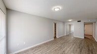 This single-story unit in Baton Rouge, Louisiana, offers a thoughtfully designed layout combining comfort and practicality. Throughout the space, wood-look plank flooring provides a cohesive, contemporary foundation, complemented by neutral gray walls and white trim that create a clean, modern aesthetic. Textured ceilings add a classic touch present in every room.

The living area is generously sized, with a front entry door flanked by a window that welcomes natural light into the space. The open feel of the room is enhanced by its simple, uncluttered design.

The kitchen features a galley-style configuration with dark gray shaker-style cabinetry lining both sides, offering substantial storage. Granite-look countertops provide ample prep space, and a stainless steel sink adds a functional detail. The wood-look flooring continues seamlessly into this area.

The bedroom is a comfortable, well-lit room with a large window overlooking greenery outside. It includes mirrored sliding closet doors and access to a built-in shelving unit, providing excellent storage options.

The bathroom is finished with a white tub-shower combination, a gray vanity with a white sink, chrome fixtures, and a large mirror with overhead lighting, maintaining the unit's consistent neutral palette.