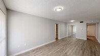 This single-story unit in Baton Rouge, Louisiana, offers a thoughtfully designed layout combining comfort and practicality. Throughout the space, wood-look plank flooring provides a cohesive, contemporary foundation, complemented by neutral gray walls and white trim that create a clean, modern aesthetic. Textured ceilings add a classic touch present in every room.

The living area is generously sized, with a front entry door flanked by a window that welcomes natural light into the space. The open feel of the room is enhanced by its simple, uncluttered design.

The kitchen features a galley-style configuration with dark gray shaker-style cabinetry lining both sides, offering substantial storage. Granite-look countertops provide ample prep space, and a stainless steel sink adds a functional detail. The wood-look flooring continues seamlessly into this area.

The bedroom is a comfortable, well-lit room with a large window overlooking greenery outside. It includes mirrored sliding closet doors and access to a built-in shelving unit, providing excellent storage options.

The bathroom is finished with a white tub-shower combination, a gray vanity with a white sink, chrome fixtures, and a large mirror with overhead lighting, maintaining the unit's consistent neutral palette.