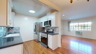 Located in the heart of West Hollywood, CA, this thoughtfully designed 2-bedroom, 1-bathroom home offers a functional and stylish single-floor layout. Warm hardwood floors run throughout the entire space, creating a cohesive and inviting atmosphere. The open living and dining area is highlighted by crown molding, recessed lighting, and a decorative chandelier, with a sliding glass door that fills the space with natural light and provides direct access to a private outdoor patio. The remodeled kitchen is well-equipped with white shaker cabinetry, dark countertops, a mosaic tile backsplash, stainless steel appliances including a gas range and French door refrigerator, and a deep single-basin sink. Both bedrooms feature hardwood flooring, individual wall-unit air conditioning, and windows that bring in natural light. The primary bedroom offers a comfortable footprint, while the second bedroom includes a walk-in closet. The bathroom is finished with large-format dark marble-style tile in the shower and tub surround, a white vanity with dark countertop, and a window for ventilation. A hallway connects all rooms, contributing to an efficient and practical floor plan throughout this West Hollywood residence.