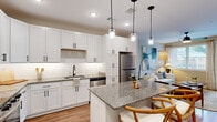 Located at 500 North Henry Street in historic Williamsburg, Virginia, this well-appointed one-bedroom, one-bathroom residence offers a cohesive and modern living experience across a single floor. The open-concept kitchen and living area serves as the heart of the home, showcasing crisp white shaker cabinetry with matte black hardware, granite countertops, a classic subway tile backsplash, and a full suite of stainless steel appliances. A central island with pendant lighting provides additional prep space and casual seating, flowing naturally into a bright, comfortable living room with a ceiling fan and windows that invite natural light and views of the surrounding brick exterior and outdoor spaces. The living area features a private entrance door, adding convenience and connectivity to the outdoors. Wood-style flooring runs throughout, lending warmth and continuity to each room. The generously sized bedroom is equipped with a ceiling fan, large windows overlooking a pool area, and direct access to a walk-in closet outfitted with wire shelving. The full bathroom impresses with a double-sink granite vanity, white cabinetry with black fixtures, and a glass-enclosed shower, all finished with the same wood-style flooring. A hallway connects the main living spaces efficiently, completing this well-designed and move-in-ready residence.