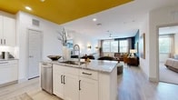 This well-appointed 2-bedroom, 2-bathroom residence offers a thoughtfully designed open-concept layout that seamlessly connects the kitchen, dining, and living areas. The kitchen is a standout feature, boasting a large granite-topped island with an undermount sink, crisp white cabinetry with matte black hardware, stainless steel appliances, and a bold yellow ceiling accent that adds a vibrant design element. Light wood-style flooring flows throughout the main living areas, enhancing the sense of openness and continuity.

The living room is generously proportioned, featuring a dramatic deep navy accent wall, large windows that invite natural light, a ceiling fan, and ample space for entertaining. The primary bedroom is a comfortable retreat with plush carpeting, a ceiling fan, natural light from a large window, and access to a dedicated closet. The second bedroom offers similar comfort and versatility. Both bathrooms are finished with granite-topped white vanities, tile surrounds, and wood-style flooring. The full bathroom includes a tub-shower combination. Two closets provide practical storage throughout the residence, completing this modern and stylishly detailed home.