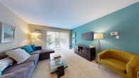 Located at 1710 Forest Cove Dr in Mount Prospect, IL, this one-bedroom, one-bathroom residence offers a thoughtfully designed single-floor layout. The entry foyer features warm hardwood flooring that transitions into the combined dining and living area, where plush carpeting and a bold teal accent wall create a vibrant yet inviting atmosphere. The living room is filled with natural light from large sliding glass doors that open to an outdoor view, complemented by vertical blinds for privacy. A ceiling fan overhead adds comfort to the dining area, which is anchored by the same striking teal accent wall. The kitchen is well-equipped with rich cherry wood cabinetry, granite-look countertops, black appliances including an electric range and over-the-range microwave, and hardwood-style flooring. The spacious primary bedroom features soft carpeting, olive-toned accent walls, generous closet space, and a bright window with teal curtains that allow natural light while maintaining a cozy feel. The bathroom includes hardwood-style flooring, a full tub-shower combo with tile surround, and a vanity with wood cabinetry. Throughout the residence, a cohesive color palette and carefully chosen finishes create a warm, livable environment.