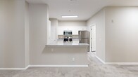 Located at 1300 Independence Place Dr in Hinesville, GA, this single-floor, 3-bedroom, 3-bathroom home offers a well-organized layout designed for comfortable everyday living. The open-concept living, dining, and kitchen area serves as the heart of the home, where a peninsula with granite countertops connects the kitchen to the living space. The kitchen is well-appointed with white shaker-style cabinetry, granite countertops, and a full suite of stainless steel appliances, including a range, microwave, dishwasher, and refrigerator. A pantry provides additional storage convenience. The bedrooms are carpeted and feature ceiling fans, ample natural light from windows with blinds, and generous closet space with double bi-fold doors. The spacious primary bedroom includes its own dedicated bathroom. Each of the three bathrooms features wood-look luxury vinyl plank flooring and granite-topped vanities with white cabinetry. The bathrooms are also equipped with grab bars, adding an accessibility-conscious touch. The dedicated laundry room includes a full-size washer and dryer, overhead wire shelving, and a folding counter. Neutral warm-beige tones throughout the home contribute to a clean, cohesive aesthetic.