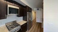 Located at 1055 E Evelyn Ave in Sunnyvale, CA, this single-floor residence offers a practical and well-organized layout across two bedrooms, one bathroom, a living room, kitchen, and hallway. The kitchen features granite-style countertops, white shaker cabinetry, hardwood-style flooring, and stainless steel appliances including a dishwasher, refrigerator, and range, providing an efficient and attractive cooking space. The living room is carpeted and filled with natural light, highlighted by a sliding glass door with vertical blinds that opens to an outdoor area, offering pleasant views of surrounding greenery. Both bedrooms are carpeted and bright, each equipped with mirrored sliding closet doors that enhance the sense of space. The primary bedroom is generously sized with dual windows that invite abundant natural light and garden views. The bathroom is clean and functional, featuring wood-style flooring, a tub-shower combination with a curtain rod, a toilet, and a vanity with granite countertops and white cabinetry. A convenient in-unit stacked washer and dryer is tucked into a dedicated closet accessible from the hallway. Neutral warm tones throughout create a cohesive and welcoming ambiance.