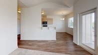 This single-floor unit presents a well-organized layout with a clean, contemporary aesthetic defined by neutral tones, warm wood-look flooring, and abundant natural light. The open-concept living and dining area serves as the heart of the space, featuring vaulted ceilings, wood-look hard flooring, a ceiling fan, and multiple windows that invite natural light. A glass door provides direct access to a private balcony with outdoor views. The living area transitions seamlessly into the kitchen via a breakfast bar with barstool seating, ideal for casual dining. The kitchen is well-appointed with flat-front light wood cabinetry, white countertops, a double sink, and black appliances including a range, microwave, and dishwasher. A pendant chandelier and recessed lighting complete the space. Two bedrooms feature plush carpeting and windows overlooking the surrounding neighborhood. Both bathrooms are finished in bright, neutral tones with light wood vanities, white countertops, and tile flooring. One bathroom includes a walk-in shower, while the other offers a combined tub-shower setup. Overall, the unit delivers a fresh, move-in-ready atmosphere with a cohesive and modern design sensibility.