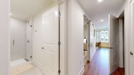 Located at 406 Harrison St in downtown Nashville, this thoughtfully designed two-bedroom, one-bathroom residence maximizes its compact footprint through an efficient, single-level layout. The open-plan kitchen and living area serves as the heart of the home, where warm wood-tone cabinetry, white upper cabinets, and stainless steel appliances — including a refrigerator, range, microwave, and dishwasher — create a clean, contemporary kitchen. Recessed lighting and light wood-look flooring carry throughout, lending a cohesive, modern aesthetic.

The living area benefits from a window that draws in natural light, complemented by sheer linen curtains for a soft, airy atmosphere. A central hallway connects the main living spaces to the bedrooms, fitted with a sliding barn door that adds a stylish, space-conscious detail. The primary bedroom offers a well-proportioned retreat with neutral tones and a walk-in closet featuring multi-tier shelving. The bathroom is finished with light tile flooring, a wood-framed vanity, white countertop, and a full glass-enclosed walk-in shower with tile surround and brushed gold hardware throughout.