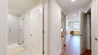 Located at 406 Harrison St in downtown Nashville, this thoughtfully designed two-bedroom, one-bathroom residence maximizes its compact footprint through an efficient, single-level layout. The open-plan kitchen and living area serves as the heart of the home, where warm wood-tone cabinetry, white upper cabinets, and stainless steel appliances — including a refrigerator, range, microwave, and dishwasher — create a clean, contemporary kitchen. Recessed lighting and light wood-look flooring carry throughout, lending a cohesive, modern aesthetic.

The living area benefits from a window that draws in natural light, complemented by sheer linen curtains for a soft, airy atmosphere. A central hallway connects the main living spaces to the bedrooms, fitted with a sliding barn door that adds a stylish, space-conscious detail. The primary bedroom offers a well-proportioned retreat with neutral tones and a walk-in closet featuring multi-tier shelving. The bathroom is finished with light tile flooring, a wood-framed vanity, white countertop, and a full glass-enclosed walk-in shower with tile surround and brushed gold hardware throughout.