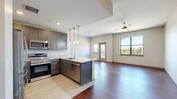 This 2-bedroom, 2-bathroom residence offers a thoughtfully designed single-floor layout that maximizes every square foot. Rich hardwood flooring flows seamlessly throughout the main living areas and bedrooms, lending warmth and continuity to the space. The open-concept living and dining area is bright and airy, benefiting from multiple windows and a glass-paneled exterior door that invites natural light while providing access to a private balcony. Ceiling fans in the living area and bedrooms enhance comfort year-round. The kitchen is a standout feature, showcasing granite countertops with an extended island, a stainless steel undermount sink with a professional-style faucet, gray shaker cabinetry, stainless steel appliances, and stylish pendant lighting overhead. Both bathrooms are finished with elegant marble-look tile flooring and walls, frameless glass shower enclosures, and modern vanities with clean white countertops. The bedrooms are generously sized, each with ceiling fans and access to well-organized closets — with five closets total offering ample storage throughout the unit. A dedicated laundry area and a connecting hallway complete the functional layout of this refined and move-in-ready home.