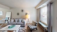 This two-floor residence offers a well-organized layout designed for comfortable everyday living. The living room provides a welcoming gathering space with neutral-toned carpeting, light-filled windows fitted with blinds and drapes, and ample room for seating arrangements. Adjacent to it, the dining area is highlighted by a large sliding glass door with vertical blinds that frames a view of the surrounding greenery, allowing natural light to flood the space.

The kitchen is efficiently designed with warm honey-toned wood cabinetry extending to the upper walls, offering generous storage. A stainless steel sink, light countertops, and a gas range are key functional features, complemented by neutral tile flooring throughout.

The bedrooms are carpeted and finished with soft, neutral walls, each offering natural light through standard windows. The rooms provide sufficient space for beds, desks, and dressers, making them versatile for various living arrangements.

The bathroom features a full-size soaking tub with an overhead shower, white surrounds with built-in shelving niches, and chrome fixtures, presenting a clean and functional design. Overall, the residence maintains a consistent, understated aesthetic throughout its two floors.