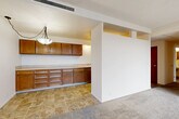Located at 4275 NE Halsey St in Portland's Hollywood neighborhood, this three-bedroom, two-bathroom unit spans a single floor and offers a practical, well-organized layout. The galley-style kitchen is a standout feature, lined with warm honey-toned wood cabinetry on both sides, generous counter space, tile flooring, and a full suite of appliances including a refrigerator, oven, and dishwasher. A pendant light illuminates the kitchen bar area, which opens toward the adjoining living space. The living room is carpeted and features a wide sliding glass door dressed with vertical blinds, allowing natural light to fill the room and providing access to an outdoor area. The space flows seamlessly from the kitchen through a hallway connecting the bedrooms and bathrooms. Each of the three carpeted bedrooms features windows that bring in natural light, with the spacious primary bedroom offering a sliding glass door. The two bathrooms are cleanly finished — one includes a full tub-shower combo with white tile surround and chrome fixtures, while the other features a vanity with a wide mirror and tile flooring. A connecting hallway ties the layout together efficiently, completing this well-structured Portland residence.