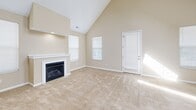 Located at 1545 Glenn Ave in Columbus, Ohio, this two-story home offers five bedrooms and three bathrooms across a well-distributed layout. The main floor opens into a spacious living room distinguished by soaring vaulted ceilings that create an airy, open feel. A fireplace serves as the focal point of the living area, which is bathed in natural light through multiple windows fitted with blinds. The kitchen is a standout feature, boasting rich dark wood cabinetry, granite countertops, stainless steel appliances, and a breakfast bar — all beneath dramatic high ceilings with recessed lighting. Hardwood flooring runs through the kitchen, while plush carpet covers the living areas and all bedrooms. The generously sized primary bedroom features vaulted ceilings and dual windows that invite natural light. Additional bedrooms vary in layout, including one with a charming angled ceiling that adds architectural interest. The three bathrooms are well-appointed, featuring tile flooring, granite-topped vanities with wood cabinetry, and tub/shower combinations, with one bathroom offering a glass-enclosed walk-in shower. Three closets provide ample storage throughout. The upper floor mirrors the spaciousness of the main level, making this a functional and comfortable home.