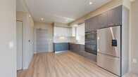 This modern 2-bedroom, 2-bathroom residence in Roseville, CA offers a thoughtfully designed single-floor layout with contemporary finishes throughout. The open-concept kitchen and living area serves as the heart of the home, featuring striking two-tone cabinetry with sleek charcoal lower cabinets and crisp white upper cabinets, light quartz countertops, a stainless steel refrigerator, and a built-in double wall oven. Light wood-style flooring flows seamlessly throughout the entire space, enhancing the clean, modern aesthetic. Floor-to-ceiling windows and large sliding glass doors in the living area and bedrooms flood the home with abundant natural light and offer open views of the surrounding Roseville streetscape. The primary bedroom is a comfortable, well-proportioned retreat that benefits from expansive windows and a wall-mounted mini-split system for personalized climate control. The second bedroom is equally bright with large windows framing urban views. Two distinct bathrooms serve the residence: one features a modern vessel sink vanity with an illuminated mirror and a dark cabinet base, while the other includes a full soaking tub and shower combination. A dedicated closet and hallway complete the efficient and well-organized floor plan.