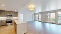 This single-floor residence at 1258 El Camino Real in Menlo Park, CA offers a thoughtfully designed open-concept layout with contemporary finishes throughout. Light hardwood flooring flows seamlessly across the main living areas, complementing the bright, neutral palette of the white walls and ceilings.

The expansive living area is anchored by a striking kitchen island with a white marble-look countertop, providing both a functional workspace and visual centerpiece. The kitchen features floor-to-ceiling cabinetry in a warm wood-grain finish, white quartz countertops, a tile backsplash, and stainless steel appliances including a gas range with microwave and a French door refrigerator. Recessed lighting and under-cabinet illumination ensure a well-lit cooking environment.

The living space opens to a private balcony through elegant French doors, flooding the interior with natural light and offering outdoor views. Bedroom spaces are bright and airy, with large windows that invite sunlight. The bathrooms are finished in a clean, minimalist style, featuring neutral tile flooring, a glass-enclosed walk-in shower in one bath, and a full tub-shower combination in another. The overall ambiance is modern, clean, and move-in ready.