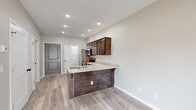 Located at 3861 W University St in Springfield, MO, this one-bedroom, one-bathroom unit offers a well-designed single-floor layout that maximizes every inch of its compact footprint. The open-concept living and kitchen area serves as the heart of the home, anchored by a peninsula with granite countertops and dark wood cabinetry that extends to the upper walls. A full suite of stainless steel appliances — including a refrigerator, range, microwave, and dishwasher — equips the kitchen for everyday functionality. Light wood-style luxury vinyl flooring runs throughout the main living area, complementing the neutral warm-gray walls and crisp white trim for a clean, modern aesthetic. Recessed lighting and a ceiling fan keep the space bright and comfortable, while a sliding glass door admits natural light and provides outdoor access from the living area. The bedroom is a cozy, private retreat with the same warm flooring and soft neutral tones, accompanied by a closet with panel doors. The bathroom features a full tub-shower surround, toilet, and matte black fixtures that add a contemporary accent. The unit is accessed through a panel-style entry door, completing a cohesive and thoughtfully designed living space.