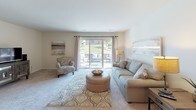 Located at 6033 Fountain Pointe in Grand Blanc, Michigan, this single-floor home offers a well-organized layout designed for comfortable everyday living. The living room is bright and inviting, featuring large sliding glass doors that open to an outdoor patio, allowing natural light to flow in while providing views of the surrounding greenery. The space flows seamlessly into a formal dining room, distinguished by classic wainscoting along the lower walls and an elegant chandelier overhead, creating a refined atmosphere suited for both everyday meals and entertaining. Rich hardwood flooring anchors the dining area, adding warmth and continuity between rooms. The kitchen is efficiently designed with a U-shaped layout, featuring dark cabinetry with decorative detailing, a double basin sink, and white appliances including a range, dishwasher, and full-size refrigerator, all set on durable wood-look flooring. The primary bedroom offers carpeted floors, a spacious closet with dark-toned bifold doors, and a calm, neutral palette that promotes relaxation. An additional bedroom carries a cozy, nature-inspired character, with carpeted floors and warm, rustic furnishing details. Throughout the home, neutral tones, plush carpeting in the bedrooms, and cohesive finishes create a welcoming and functional living environment.